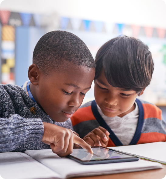 Dois meninos usando um tablet juntos na escola