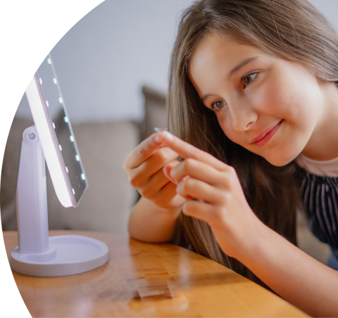 Menina sorrindo olhando para uma luminária de mesa